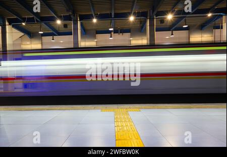 Beautiful image of the captured blurred motion of a train passing a station at night in Jakarta. Stock Photo