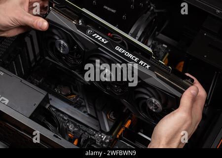 UKRAINE, DNIPRO, FEBRUARY 23, 2023: MSI Geforce RTX graphics card, Installing video card in an open case of PC. Hardware components for build PC or mi Stock Photo