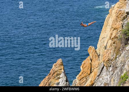 Acapulco, Mexico - 17 January 2024: One of the famous cliff divers at La Quebrada diving into the sea from a high diving platform Stock Photo