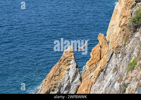 Acapulco, Mexico - 17 January 2024: One of the famous cliff divers at La Quebrada diving into the sea from a high diving platform Stock Photo