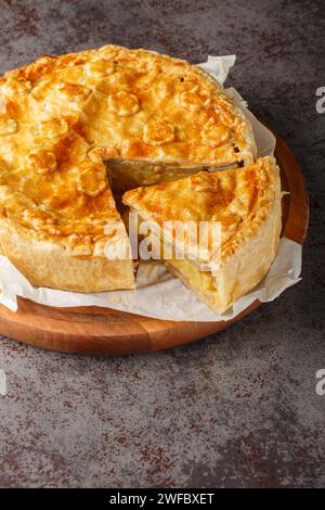 Cholera pie is a pastry filled with potatoes, vegetables, fruits and cheese, originated from the Valais region of Switzerland closeup on the wooden bo Stock Photo