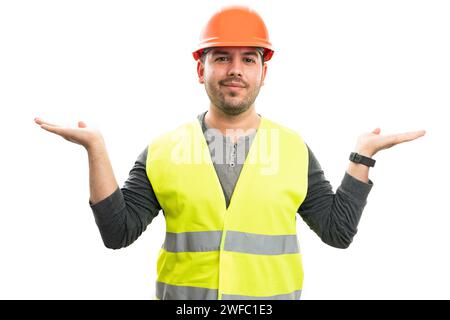 Friendly adult builder man wearing safety hardhat and yellow vest uniform holding palms as presenting blank copyspace for advertising text isolated on Stock Photo