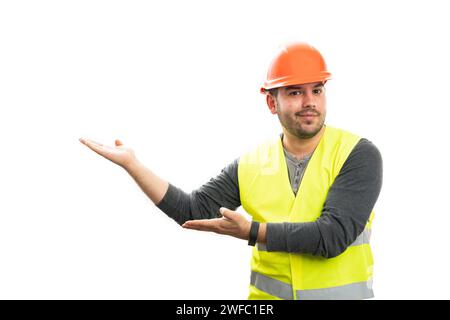Adult friendly male builder in vest and safety helmet work attire smiling as presenting blank copyspace for text using palms isolated on white backgro Stock Photo