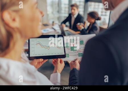 Close up of colleagues discussing biz related problem in the office and using digital tablet Stock Photo