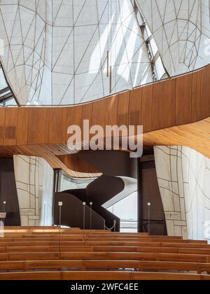 Temple interior with timber benches, balcony, stairway and view of translucent wings. Baháí Temple of South America, Santiago, Chile. Architect: Hari Stock Photo