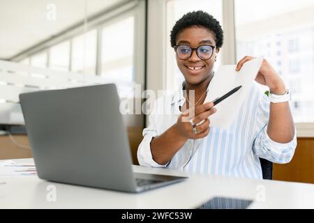 Diverse office employees concept. African-American woman using laptop for online video meeting, talking with colleagues or coworkers online, presenting business plan. Teacher conducting webinar Stock Photo