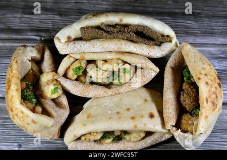 Background of fried shrimps, beef brain, beef liver slices deep fried in oil and served with parsley in a traditional Egyptian flat bread with wheat b Stock Photo