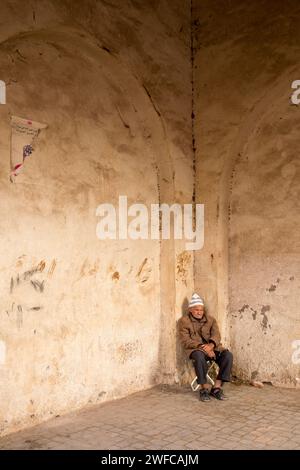 North Africa Morocco Marrakech Marrakesh medina Moroccan man sat on a chair in street with old walls Stock Photo