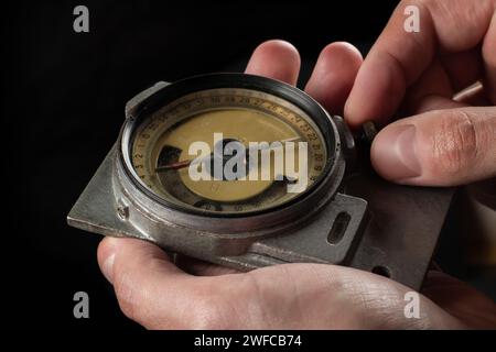 Old mining compass in hand on dark background close up. Stock Photo