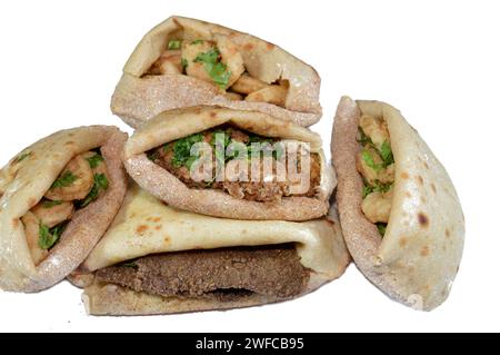 Background of fried shrimps, beef brain, beef liver slices deep fried in oil and served with parsley in a traditional Egyptian flat bread with wheat b Stock Photo