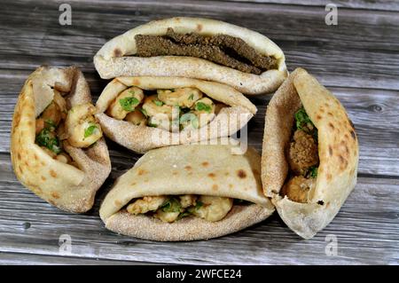 Background of fried shrimps, beef brain, beef liver slices deep fried in oil and served with parsley in a traditional Egyptian flat bread with wheat b Stock Photo