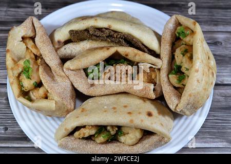 Background of fried shrimps, beef brain, beef liver slices deep fried in oil and served with parsley in a traditional Egyptian flat bread with wheat b Stock Photo