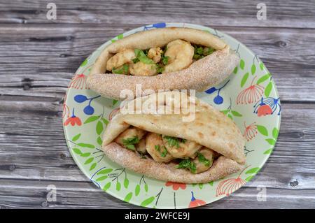 Fried shrimps covered with flour and fried in deep hot oil, a sandwich of fried shrimps in a traditional Egyptian flat bread with wheat bran and flour Stock Photo