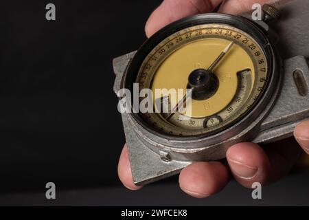 Old mining compass in hand on dark background close up. Stock Photo