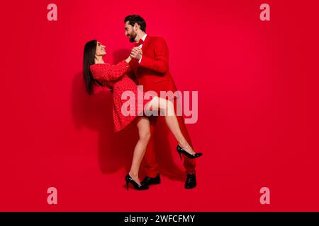 Full body photo of attractive young couple dancing have fun valentine day dressed stylish elegant clothes isolated on red color background Stock Photo