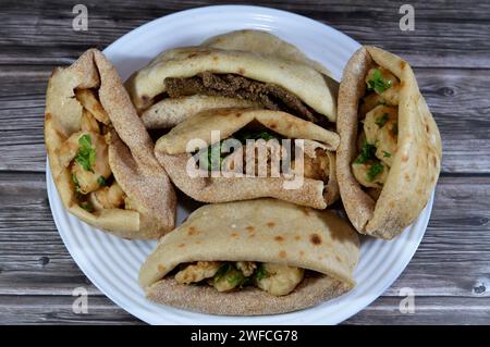 Background of fried shrimps, beef brain, beef liver slices deep fried in oil and served with parsley in a traditional Egyptian flat bread with wheat b Stock Photo