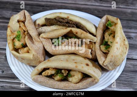 Background of fried shrimps, beef brain, beef liver slices deep fried in oil and served with parsley in a traditional Egyptian flat bread with wheat b Stock Photo