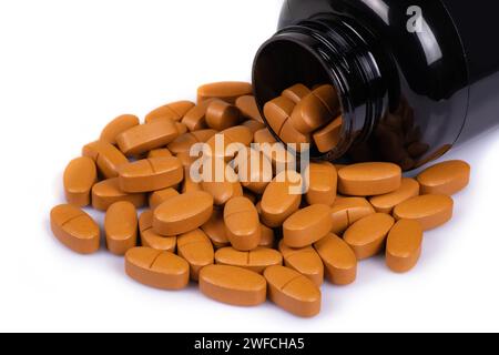 Brown pills medication in pile on white background. Stock Photo