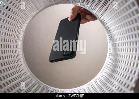 a man throws a non-working smartphone into a trash can. Bottom view from the trash can. The problem of recycling and pollution of the planet with garb Stock Photo