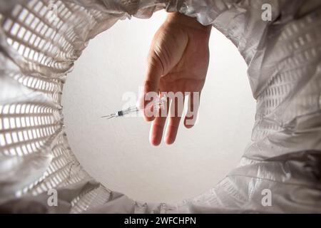 Hand throws syringe into trash bin with package. Inside view. Stock Photo