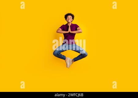 Full length photo of concentrated focused guy wear stylish violet polo meditate pray two hands touch isolated on yellow color background Stock Photo