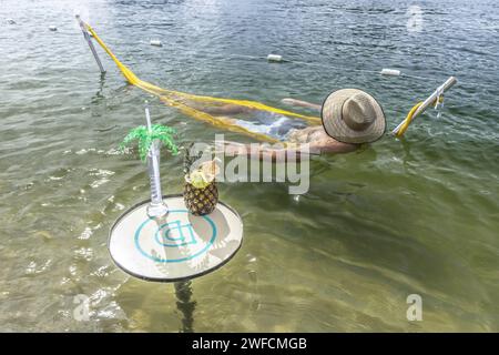 Person lying in rest hammock on the river beach of the São Francisco River - Stock Photo
