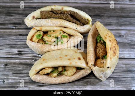 Background of fried shrimps, beef brain, beef liver slices deep fried in oil and served with parsley in a traditional Egyptian flat bread with wheat b Stock Photo