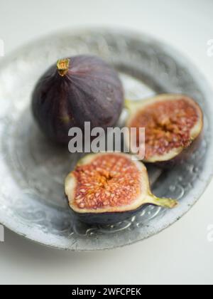 One whole fig and the second cut in half on a white table. Selective focus Stock Photo