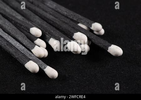 Black wooden matches on black background. Matchsticks with bright blue heads macro. Scattered wooden matches without box close-up. Design element for Stock Photo