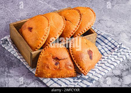 Three pastries in a rustic wooden box placed on a charming blue and white checked cloths Stock Photo