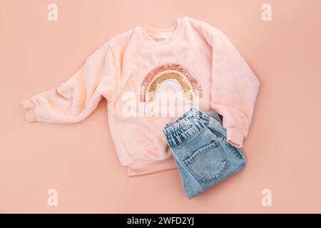 Children's pink sweater and blue jeans on a pink background Stock Photo