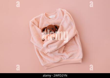 Soft pink jacket hugging a stuffed toy on a pink background Stock Photo
