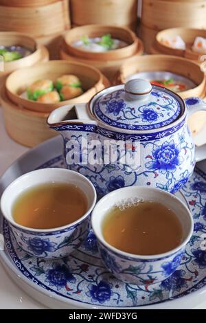 Two Cups of Hot Chinese Oolong Tea with Blurry Assorted Dim Sum Dishes in Background Stock Photo