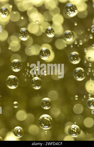 Background of gold bubbles against gold bokeh, close up. Stock Photo