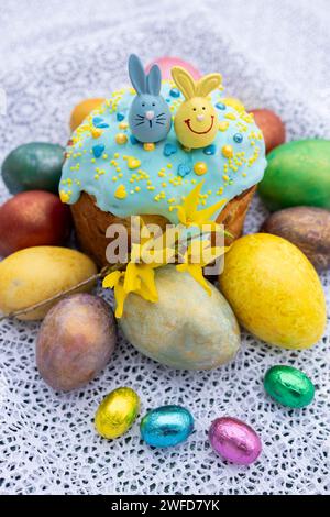 On the lace lie colorful Easter eggs, homemade Easter glazed Easter cake, chocolate eggs and souvenir bunnies. Easter concept. Christ is risen. Orthod Stock Photo
