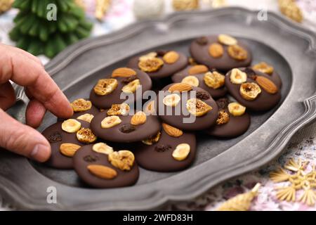 homemade chocolate mendiants with traditional toppings; almonds, raisins, hazelnuts, fig.   French Christmas sweets. Stock Photo
