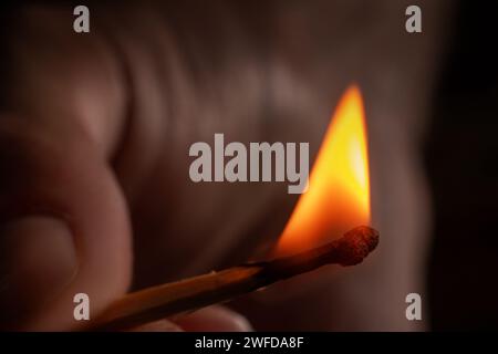 Hand holding burning match stick. Photo on a black background. Stock Photo