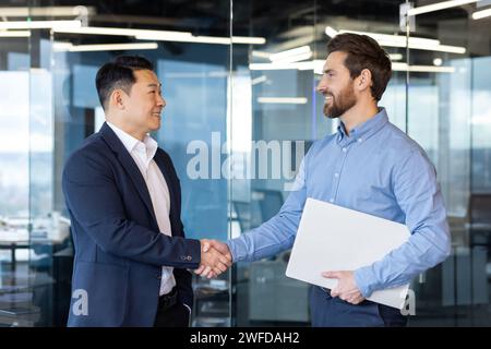 Professional and friendly handshake between two businessmen in an office setting, symbolizing partnership, agreement, and teamwork. Stock Photo
