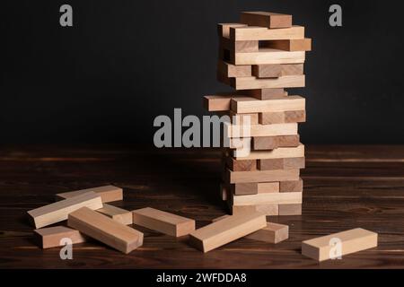 Jenga tower made of wooden blocks on wooden background, space for text. Stock Photo