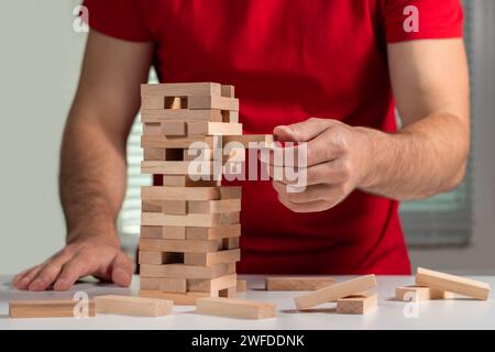 The tower from wooden blocks and man's hand take one block. Stock Photo