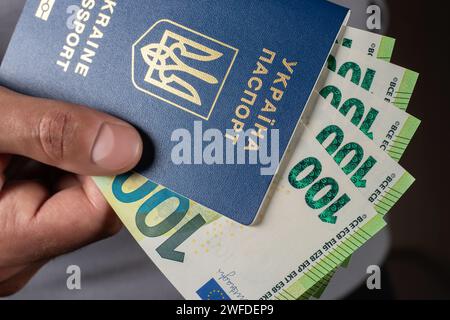 ukrainian passport and 100 euro banknotes in hand. Stock Photo