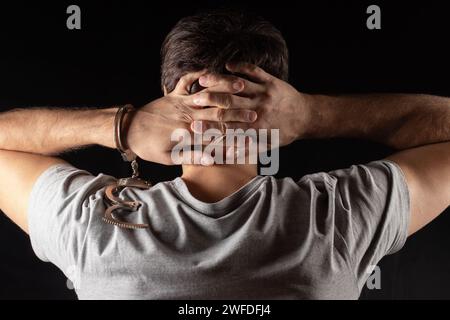 Arrested man in handcuffs with handcuffed hands behind back in prison. Stock Photo
