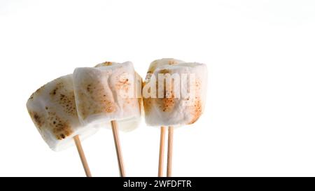 Bamboo sticks with roasted marshmallows on white backgrop Stock Photo