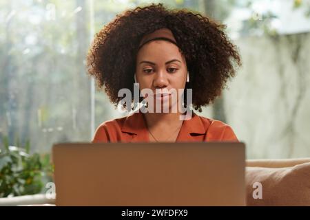 Portrait of woman watching educational video on laptop at home Stock Photo