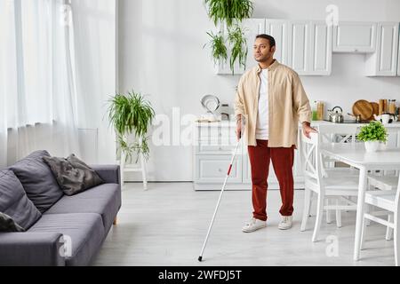 attractive blind indian man in casual cozy homewear using walking stick while at home, disabled Stock Photo