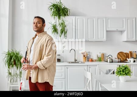 handsome blind indian man in everyday homewear using walking stick while at home, disabled Stock Photo