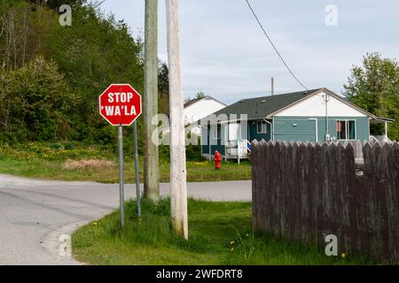 A stop sign in the Namgis First Nation community includes indigenous language, in a residential neighbourhood on Cormorant Island in British Columbia Stock Photo