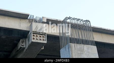 Round iron reinforcing bars or rebars jutting out of unfinished pillars and beams at an ongoing flyover project Stock Photo