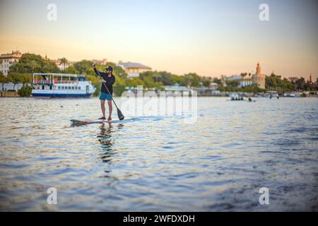 Man practicing paddle surf on the Guadalquivir river in the center of the city of Seville, Spain. Stock Photo