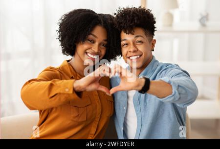 Cheerful young african american woman and man making heart gesture with hands Stock Photo